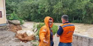 Agentes da Defesa Civil inspecionam prédio em São José após o desabamento de um muro causado pela forte chuva.