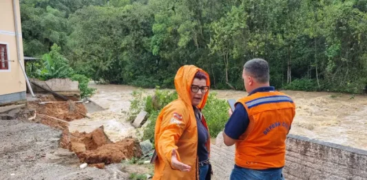 Agentes da Defesa Civil inspecionam prédio em São José após o desabamento de um muro causado pela forte chuva.