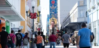 Pessoas caminham pelo centro de Florianópolis em dia ensolarado, ilustrando a movimentação urbana e o cotidiano da população no contexto da matéria sobre distribuição de renda em Santa Catarina.