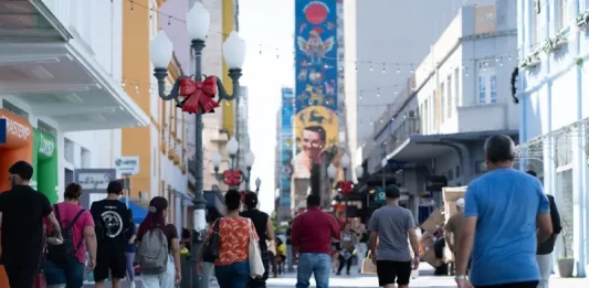 Santa Catarina tem a melhor distribuição de renda do país, aponta IBGE Pessoas caminham pelo centro de Florianópolis em dia ensolarado, ilustrando a movimentação urbana e o cotidiano da população no contexto da matéria sobre distribuição de renda em Santa Catarina.