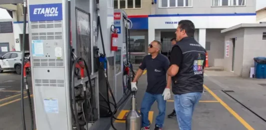 Fiscais do Procon realizam teste de qualidade em bomba de combustível com equipamento de medição ao lado da área de etanol comum durante operação de inspeção em postos de combustíveis da cidade.