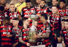 Jogadores do Flamengo erguem a taça comemorando o tetra da Libertadores, celebrando a conquista histórica do clube.