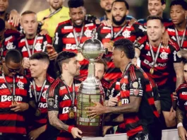 Jogadores do Flamengo erguem a taça comemorando o tetra da Libertadores, celebrando a conquista histórica do clube.
