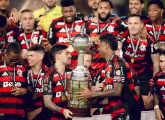 Jogadores do Flamengo erguem a taça comemorando o tetra da Libertadores, celebrando a conquista histórica do clube.