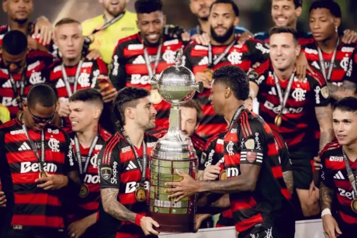 Jogadores do Flamengo erguem a taça comemorando o tetra da Libertadores, celebrando a conquista histórica do clube.