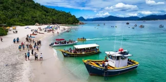 A imagem mostra embarcações realizando o desembarque de visitantes na Ilha do Campeche, ilustrando o transporte turístico que atende a operação de acesso e visitação ao local.