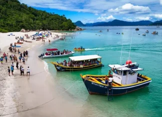A imagem mostra embarcações realizando o desembarque de visitantes na Ilha do Campeche, ilustrando o transporte turístico que atende a operação de acesso e visitação ao local.