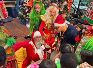 Papai Noel rodeado de crianças durante a ação Natal Solidário da Celesc, ilustrando o momento de confraternização e entrega de presentes.