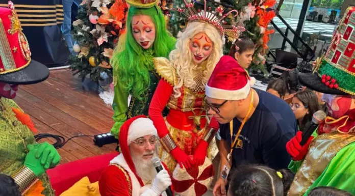 Natal Solidário da Celesc mobiliza voluntários e leva alegria a crianças acolhidas Papai Noel rodeado de crianças durante a ação Natal Solidário da Celesc, ilustrando o momento de confraternização e entrega de presentes.