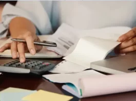 São José cria programa Nota Premiada Josefense para incentivar a emissão de notas fiscais Pessoa confere notas fiscais e faz cálculos com calculadora e notebook, ilustrando a organização necessária para participar da Nota Premiada Josefense.