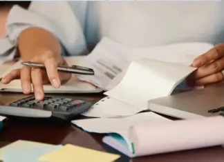 São José cria programa Nota Premiada Josefense para incentivar a emissão de notas fiscais Pessoa confere notas fiscais e faz cálculos com calculadora e notebook, ilustrando a organização necessária para participar da Nota Premiada Josefense.