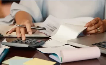 São José cria programa Nota Premiada Josefense para incentivar a emissão de notas fiscais Pessoa confere notas fiscais e faz cálculos com calculadora e notebook, ilustrando a organização necessária para participar da Nota Premiada Josefense.