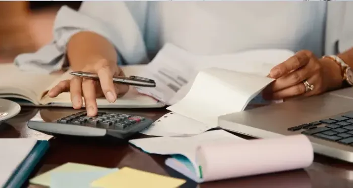 São José cria programa Nota Premiada Josefense para incentivar a emissão de notas fiscais Pessoa confere notas fiscais e faz cálculos com calculadora e notebook, ilustrando a organização necessária para participar da Nota Premiada Josefense.