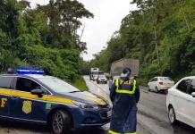 Agente da Polícia Rodoviária Federal ao lado de uma viatura, monitorando o fluxo de veículos nas BRs de Santa Catarina durante o período do Réveillon.