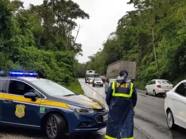 Agente da Polícia Rodoviária Federal ao lado de uma viatura, monitorando o fluxo de veículos nas BRs de Santa Catarina durante o período do Réveillon.