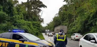 Agente da Polícia Rodoviária Federal ao lado de uma viatura, monitorando o fluxo de veículos nas BRs de Santa Catarina durante o período do Réveillon.