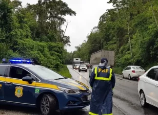 Agente da Polícia Rodoviária Federal ao lado de uma viatura, monitorando o fluxo de veículos nas BRs de Santa Catarina durante o período do Réveillon.