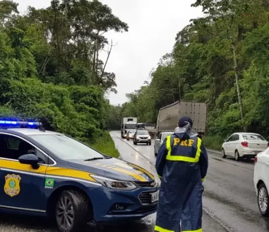 Agente da Polícia Rodoviária Federal ao lado de uma viatura, monitorando o fluxo de veículos nas BRs de Santa Catarina durante o período do Réveillon.