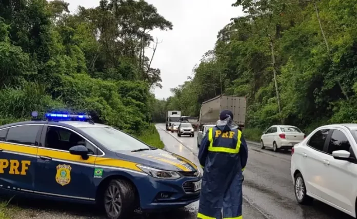Agente da Polícia Rodoviária Federal ao lado de uma viatura, monitorando o fluxo de veículos nas BRs de Santa Catarina durante o período do Réveillon.