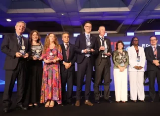 Secretário de Estado da Fazenda, Cleverson Siewert, recebe prêmio de transparência pública no palco, acompanhado de representantes de outros estados.