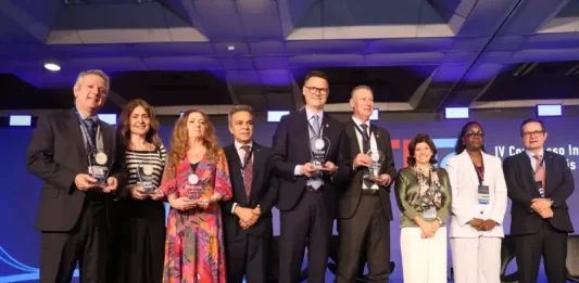 Secretário de Estado da Fazenda, Cleverson Siewert, recebe prêmio de transparência pública no palco, acompanhado de representantes de outros estados.