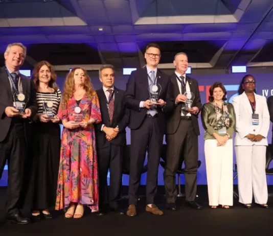 Secretário de Estado da Fazenda, Cleverson Siewert, recebe prêmio de transparência pública no palco, acompanhado de representantes de outros estados.