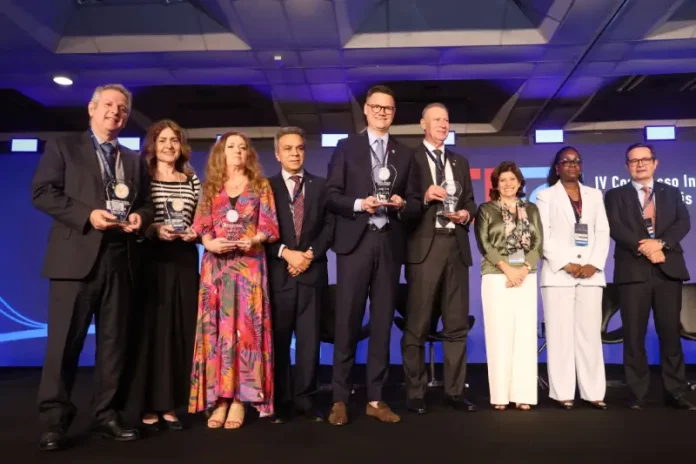 Secretário de Estado da Fazenda, Cleverson Siewert, recebe prêmio de transparência pública no palco, acompanhado de representantes de outros estados.