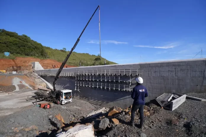 Programa Energia Boa1 Pessoa com capacete observa obra de usina hidrelétrica em construção, ilustrando o avanço das estruturas ligadas ao Programa Energia Boa.
