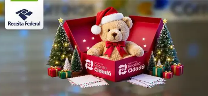 Imagem institucional da Receita Federal com urso de pelúcia usando gorro de Natal dentro de uma caixa da campanha Receita Cidadã, ao lado de árvores natalinas e presentes, simbolizando doações para o Papai Noel dos Correios.