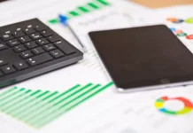 teclado e tablet sobre relatórios financeiros com gráficos, ilustrando análise de dados e planejamento de investimentos públicos