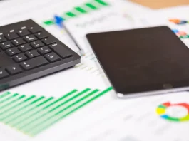 teclado e tablet sobre relatórios financeiros com gráficos, ilustrando análise de dados e planejamento de investimentos públicos