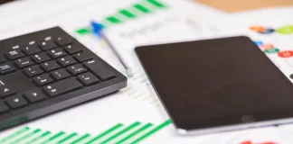 teclado e tablet sobre relatórios financeiros com gráficos, ilustrando análise de dados e planejamento de investimentos públicos