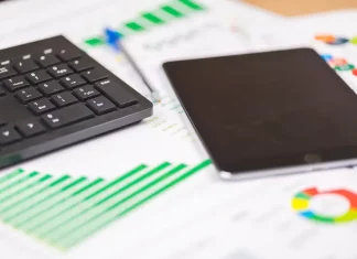 teclado e tablet sobre relatórios financeiros com gráficos, ilustrando análise de dados e planejamento de investimentos públicos
