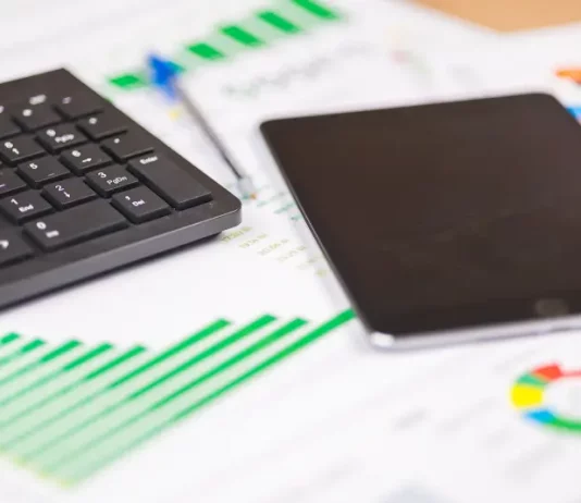 teclado e tablet sobre relatórios financeiros com gráficos, ilustrando análise de dados e planejamento de investimentos públicos