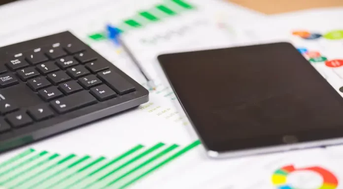 Santa Catarina encerra 2025 com R$ 5,5 bilhões em investimentos, alta do PIB e equilíbrio fiscal teclado e tablet sobre relatórios financeiros com gráficos, ilustrando análise de dados e planejamento de investimentos públicos