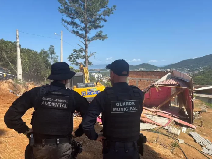 agentes da Guarda Municipal e da Guarda Municipal Ambiental acompanham a demolição de construções irregulares para garantir segurança e cumprimento da ação