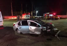 Carro com a frente destruída após colisão frontal na SC-405, enquanto equipes do Corpo de Bombeiros e do SAMU realizam atendimento às vítimas durante a noite.