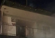 Imagem mostra a fachada de uma residência atingida por incêndio, com fumaça saindo do imóvel durante atendimento do Corpo de Bombeiros em São José.