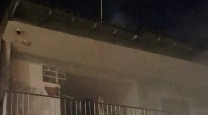 Imagem mostra a fachada de uma residência atingida por incêndio, com fumaça saindo do imóvel durante atendimento do Corpo de Bombeiros em São José.