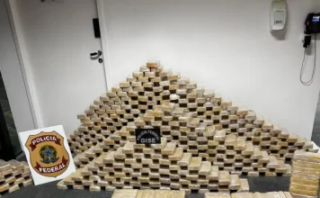 Tabletes de cocaína empilhados ao lado do símbolo da Polícia Federal, mostrando a quantidade de drogas apreendidas durante a operação em Blumenau.