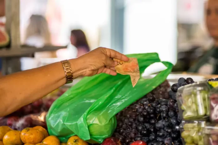 Mulher pagando R$ 20 por frutas na feira, representando a baixa taxa de pobreza e extrema pobreza em Santa Catarina.
