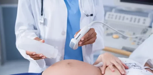 Foto mostra uma gestante em exame de ultrassom, ilustrando cuidados do pré-natal e a humanização da assistência obstétrica.