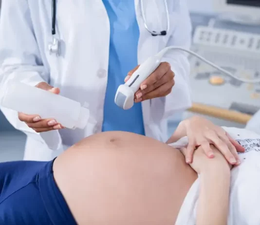 Foto mostra uma gestante em exame de ultrassom, ilustrando cuidados do pré-natal e a humanização da assistência obstétrica.