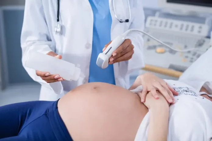 mulher-gravida-recebendo-uma-ultra-sonografia-no-estomago Foto mostra uma gestante em exame de ultrassom, ilustrando cuidados do pré-natal e a humanização da assistência obstétrica.