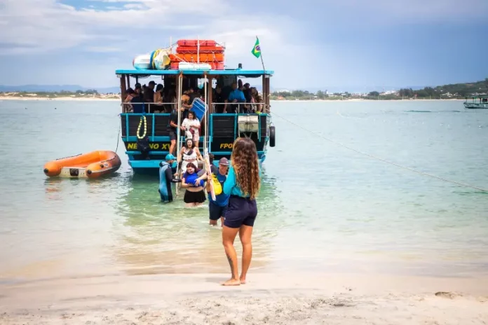 Embarcação de transporte turístico desembarca passageiros na Ilha do Campeche, ilustrando o acesso de visitantes à unidade de conservação.