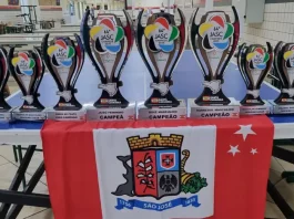 Conjunto de troféus conquistados por São José no Jasc expostos sobre uma mesa, destacando os resultados e o desempenho das equipes do município.