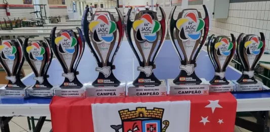 Conjunto de troféus conquistados por São José no Jasc expostos sobre uma mesa, destacando os resultados e o desempenho das equipes do município.
