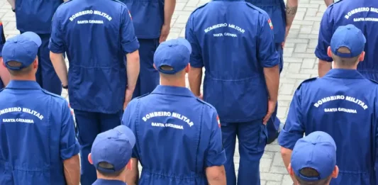 Grupo de bombeiros militares de Santa Catarina, vistos de costas e uniformizados, reunidos em formação, representando o efetivo do Corpo de Bombeiros Militar de Santa Catarina e ilustrando a abertura do processo seletivo para o Serviço Militar Estadual Temporário (SEMET), que visa reforçar as atividades operacionais da corporação em diversas regiões do estado.