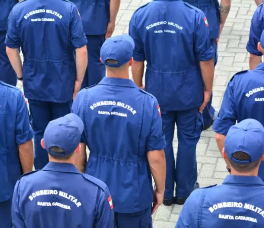 Grupo de bombeiros militares de Santa Catarina, vistos de costas e uniformizados, reunidos em formação, representando o efetivo do Corpo de Bombeiros Militar de Santa Catarina e ilustrando a abertura do processo seletivo para o Serviço Militar Estadual Temporário (SEMET), que visa reforçar as atividades operacionais da corporação em diversas regiões do estado.