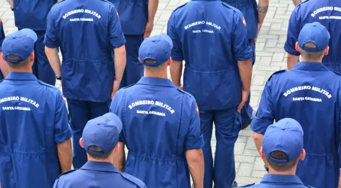 Grupo de bombeiros militares de Santa Catarina, vistos de costas e uniformizados, reunidos em formação, representando o efetivo do Corpo de Bombeiros Militar de Santa Catarina e ilustrando a abertura do processo seletivo para o Serviço Militar Estadual Temporário (SEMET), que visa reforçar as atividades operacionais da corporação em diversas regiões do estado.